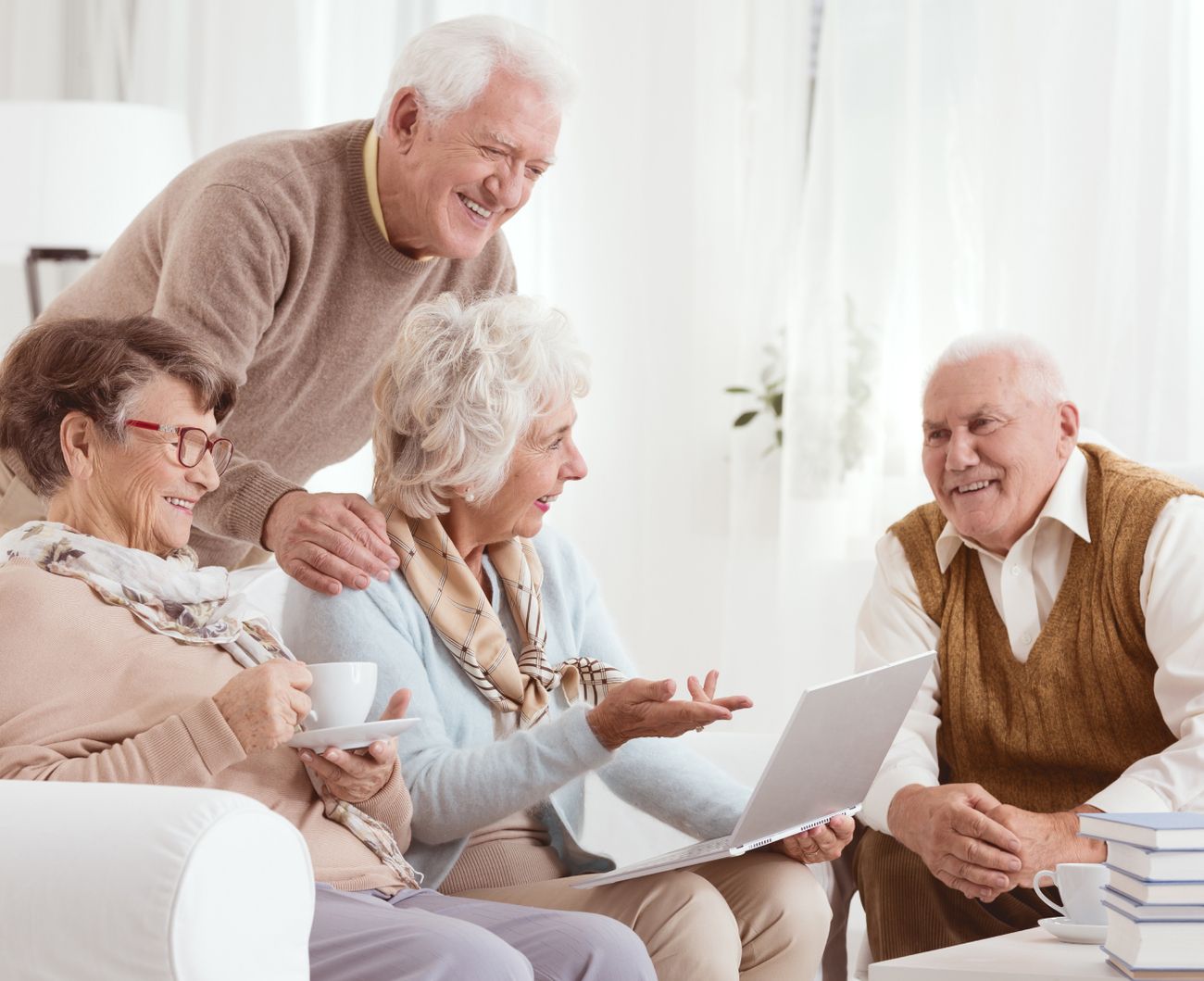 Eine Gruppe älterer Menschen sitzt gemütlich auf einer Couch und unterhält sich freundlich miteinander.