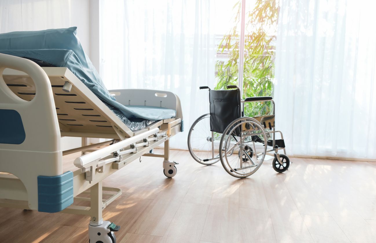Ein Krankenhausbett mit einem Rollstuhl davor.