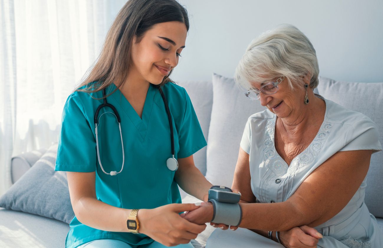 Eine Krankenschwester führt eine Blutdruckmessung bei einer älteren Dame durch.