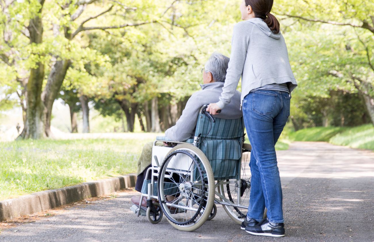 Eine Frau geht mit einem Mann in einem Rollstuhl spazieren