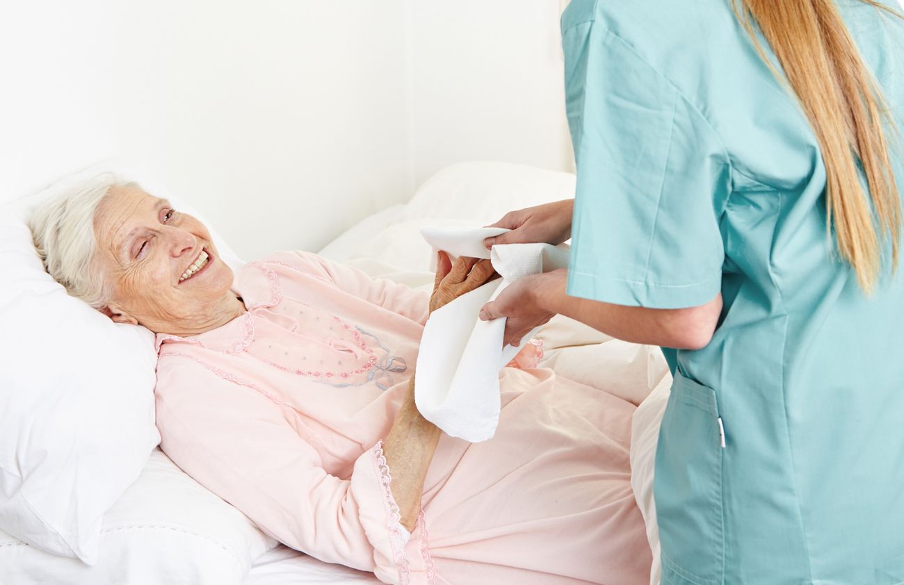 Eine Krankenschwester unterstützt eine ältere Frau im Bett und sorgt für ihre Bedürfnisse und ihr Wohlbefinden.